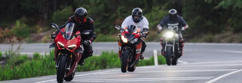 Riders on a curvy road through a forest