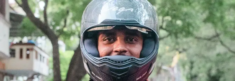 A rider in red holding a helmet