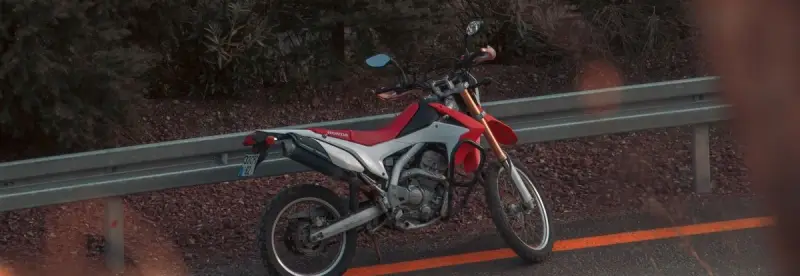 A motorbike with trees and a lake behind it
